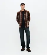 Pantalón de jean para hombre de corte recto y cintura media, confeccionado en algodón con lavado oscuro y efecto desgastado. Cuenta con cierre frontal con botón, pasadores para cinturón y bolsillos funcionales.