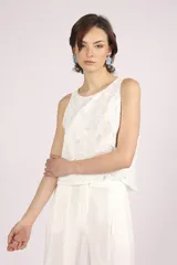 Blusa blanca de broderie con cuello redondo y sin mangas.