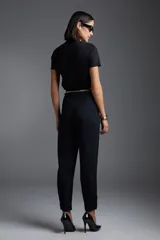 Remera negra de manga corta con aplique de flor en el hombro y cinturón de cadena dorada.