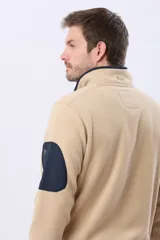 Buzo de abrigo confeccionado en tejido polar térmico, diseñado para mantener el calor y ofrecer resistencia al viento. Presenta un cuello alto con cierre frontal de broches, bolsillos laterales con cierre y un bolsillo adicional con cierre en la manga izquierda.