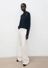 Sweater de punto color azul marino, con cuello redondo y mangas largas que presentan una línea blanca decorativa a lo largo de las costuras raglán y los puños.