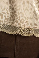 Top negro de tirantes finos con detalle de encaje en el escote y el ruedo, con estampa animal print sutil.