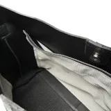 Cartera tipo hobo de cuero negro con textura granulada y correa de hombro ajustable.