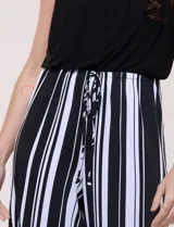 Enterito largo sin mangas con cuerpo negro de escote alto y pantalón wide leg de rayas verticales blancas y negras, con cintura elastizada y cordón ajustable.