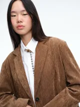 Blazer de pana color marrón con solapas clásicas, cierre frontal de dos botones y bolsillos laterales con solapa.