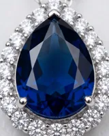 Collar de plata 925 con cadena fina y dije en forma de lágrima, con un cristal central azul zafiro rodeado por pequeñas circonias brillantes.