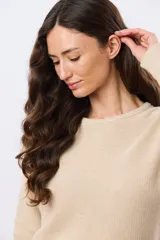 Buzo tejido liso de manga larga con cuello redondo, confeccionado en algodón de tejido grueso. Presenta bordes acanalados en el cuello, los puños y la cintura, con un pequeño detalle de placa metálica en el lateral inferior.