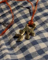 Collar con dije de bronce macizo con forma orgánica irregular, similar a un coral, suspendido de un cordón negro de seda natural anudado.