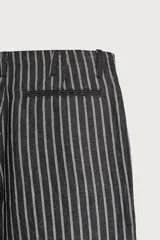 Pantalón relaxed fit de mezclilla con mezcla de algodón y lino, con diseño de rayas verticales oscuras y claras. Cuenta con cintura ajustable con cordón, bolsillos frontales, bolsillo cerillero y cierre frontal con cremallera y gancho metálico.