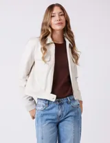 Chaqueta color beige de símil gamuza, con cuello solapa, cierre frontal y bolsillos aplicados en el pecho. Puños con botón a presión.