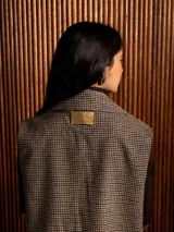 Chaleco de paño con estampado de pata de gallo, diseño cruzado con botones frontales, solapas amplias y detalle de pines decorativos en el pecho.