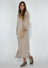 Vestido largo color crudo, con escote en V, mangas largas abullonadas y corte holgado.