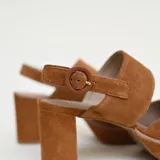 Zapato de gamuza color marrón, con plataforma delantera, taco ancho, puntera cerrada y tira ajustable al talón con hebilla.
