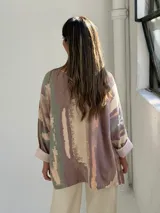 Sweater de punto con diseño abstracto en tonos tierra, verde y beige, de corte holgado, cuello en V y mangas largas con puños vueltos.