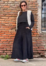 Pantalón tipo palazzo de tiro alto, confeccionado en plush de algodón con textura suave. Presenta un diseño amplio y fluido, con bolsillos laterales y una faja ancha en la cintura que brinda ajuste y comodidad.