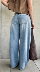 Jean de denim celeste de corte barrel, tiro bajo, con roturas y detalles desgastados en la rodilla.