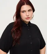 Vestido chemise midi color negro confeccionado en viscosa, de corte recto y holgado. Cuenta con cuello camisero, mangas cortas y cierre frontal con botones al tono.