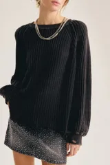 Sweater de punto grueso acanalado color negro, de corte oversized con mangas amplias y terminación deshilachada en el ruedo.