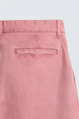 Pantalón relaxed fit color rosado, confeccionado en tejido de algodón con efecto lavado. Presenta pliegues frontales, bolsillos delanteros y bolsillos traseros de vivo. Cierre frontal con cremallera y botón.