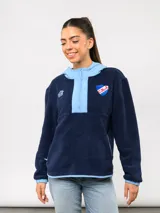 Buzo de micropolar azul marino con capucha y medio cierre frontal. Presenta detalles en tela de contraste color celeste en la capucha, la solapa del cierre y los puños. Incluye el escudo del Club Nacional de Football y el logo de Umbro bordados en el pecho.