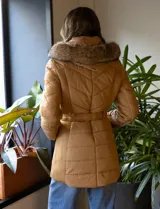 Campera de abrigo negra marca Michael Kors, con capucha desmontable con borde de piel sintética, cierre central con botones a presión y cierre oculto, bolsillos delanteros con cierre, puños elastizados, cintura con pasadores y cinto elastizado con hebilla.