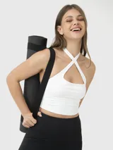 Top deportivo corto de color blanco con diseño de tirantes cruzados en el frente y escote tipo halter. Cuenta con sujetador integrado y almohadillas removibles.