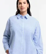 Camisa de corte clásico y largo, confeccionada en tejido anarruga con estampado de rayas verticales en tonos azul y blanco. Presenta cuello inglés, cierre frontal abotonado y mangas largas con puños.