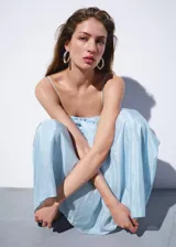 Vestido midi celeste de lino con escote recto, tirantes finos, cuerpo fruncido y falda evasé con volados.