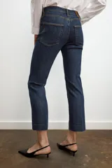 Jeans de mezclilla azul claro, tiro medio, corte recto y ligeramente acampanado en el bajo. Presenta cinco bolsillos y cierre frontal con cremallera y botón metálico.