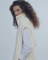 Chaleco largo de punto trenzado color gris con cuello alto y cierre frontal con cremallera metálica.