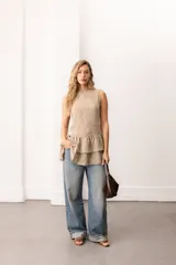 Vestido corto sin mangas de encaje negro, con escote bote y terminación de volados superpuestos.