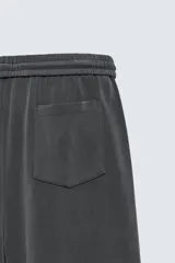 Pantalón jogger de corte wide fit confeccionado en tejido fluido con viscosa. Presenta un efecto lavado, cintura elástica ajustable con cordón, pliegues frontales, bolsillos laterales y un bolsillo trasero de plastrón.