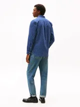 Camisa Tommy Hilfiger de corte regular, confeccionada en tejido Oxford de algodón con textura y diseño de rayas verticales azules y blancas. Cuenta con cuello abotonado, mangas largas con puños abotonados y logo bordado en el pecho.