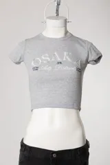 Remera baby tee de morley color chocolate, de calce ajustado al cuerpo y manga corta, con cuello redondo y diseño estampado frontal.