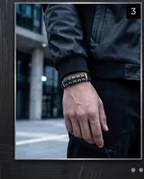 Pulsera de diseño moderno compuesta por una banda de goma negra con eslabones rectangulares de acero inoxidable entrelazados.