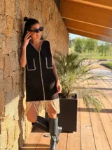 Vestido corto negro sin mangas, con escote en V y detalle de flecos en el ruedo. Presenta bordados en color blanco en el escote, los bolsillos y el centro del vestido.