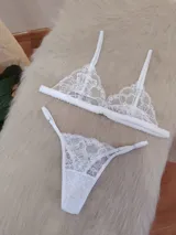 Conjunto de lencería compuesto por un bralette triangular de encaje floral con breteles regulables y una bombacha tipo tanga a juego con detalles de encaje y tiras ajustables.