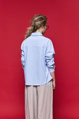 Camisa de manga larga color blanco, con cuello clásico y cierre frontal de botones de nácar. Presenta un corte cómodo y versátil.