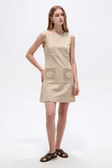 Vestido corto blanco de viscosa, sin mangas, con cuello redondo a la base y bolsillos frontales con apliques bordados.