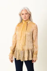 Blusa dorada de organza plisada con bordado de perlas, lazo en el cuello y musculosa debajo.