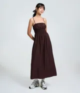 Vestido midi de viscosa certificada, color marrón oscuro, con escote recto y breteles finos. Presenta un canesú fruncido con efecto smock o lastex en el busto y falda de corte amplio.