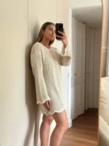 Vestido corto de tejido calado con patrón de ondas, confeccionado en algodón y lurex. Presenta mangas largas, cuello redondo y diseño holgado.