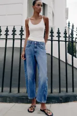 Jeans de tiro medio con cinco bolsillos, pernera holgada y diseño barrel, con costuras decorativas frontales y cierre de cremallera y botón.