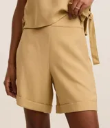 Bermuda Marfinno de talle alto y corte recto, confeccionada en viscosa twill color beige. Cuenta con cierre lateral mediante cremallera y detalle de ruedo italiano o plegado hacia afuera.