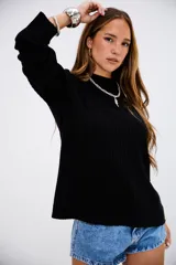 Sweater de punto acanalado en color negro, con cuello redondo y mangas largas. Presenta un diseño de corte recto y textura acanalada vertical.