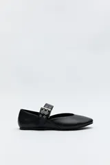 Balerina negra de cuero sintético con punta fina y tira ancha con hebilla metálica y ojalillos.