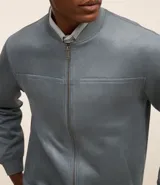 Chaqueta bomber azul marino lisa, con cierre frontal, cuello redondo y bolsillos laterales.