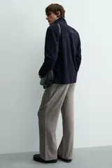 Pantalón relaxed fit color marrón con patrón de espiga, confeccionado en tejido con viscosa. Presenta pliegues frontales, bolsillos laterales y bolsillos traseros de vivo. Cierre frontal con cremallera y botón.