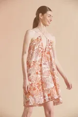 Vestido corto con estampado floral en tonos naranja y blanco, con cuello halter y volados en el ruedo.