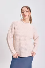 Buzo de punto con textura en color crudo, de cuello alto tejido en rib y manga larga.